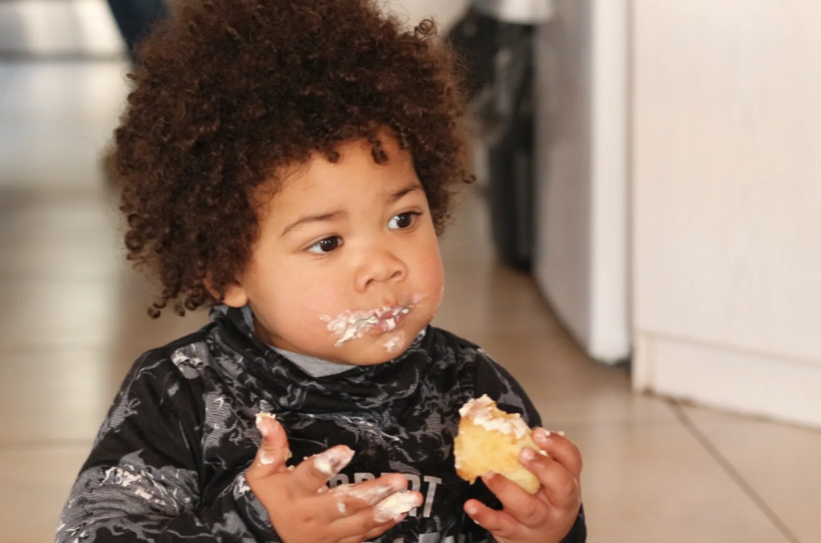 A young child happily eating buttered bread